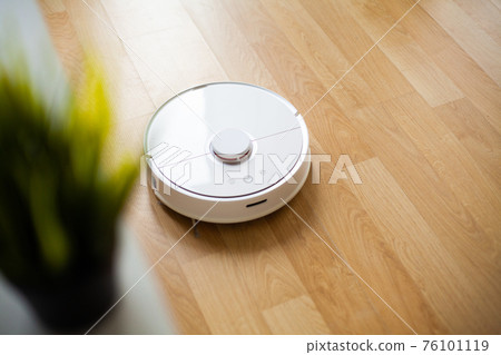 Vacuum cleaner robot runs on wood floor in a office Vacuum cleaner robot runs on wood floor in a office 76101119