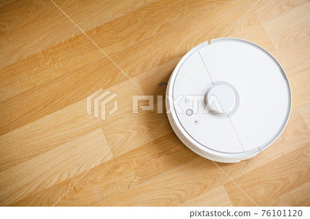 Vacuum cleaner robot runs on wood floor in a office Vacuum cleaner robot runs on wood floor in a office 76101120