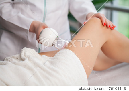 Woman getting anti-cellulite massage of leg with use of vacuum cans Woman getting anti-cellulite massage of leg with use of vacuum cans 76101148