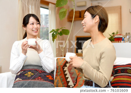 Women having a conversation while relaxing at home 76101609