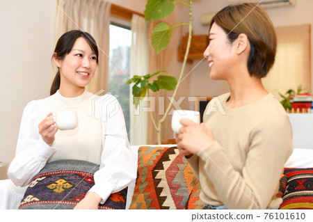 Women having a conversation while relaxing at home 76101610