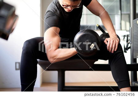 亞洲男子在訓練健身房做啞鈴捲髮 亞洲男子在訓練健身房做啞鈴捲髮 76102456