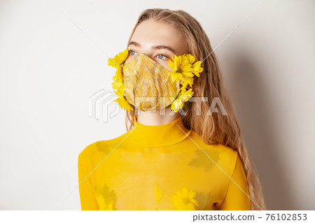 Woman in mask with yellow flowers in studio 76102853