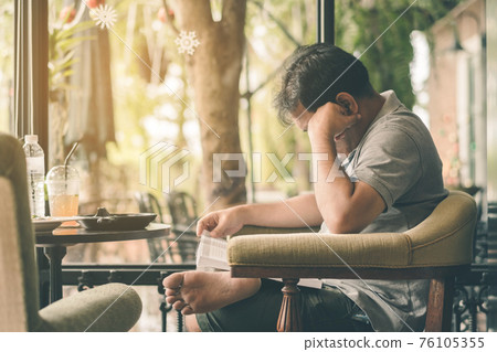 Asian man read a book in a coffee shop. Asian man read a book in a coffee shop. 76105355