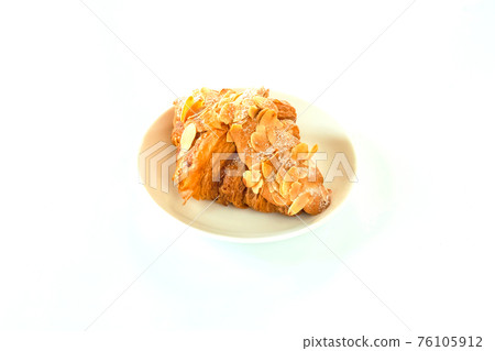 Freshly baked butter almond croissant on white plate. Top of icing sugar and almond slide, homemade isolate with white background. French pastry. traditional French breakfast. 76105912