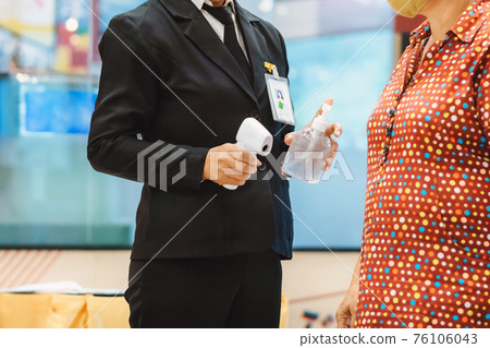 Hand of female security officer holds alcohol gel bottle to serve customers to prevent the spread of germs and bacteria and avoid infections Corona virus (Covid-19) before entering the mall. Hand of female security officer holds alcohol gel bottle to serve customers to prevent the spread of germs and bacteria and avoid infections Corona virus (Covid-19) before entering the mall. 76106043