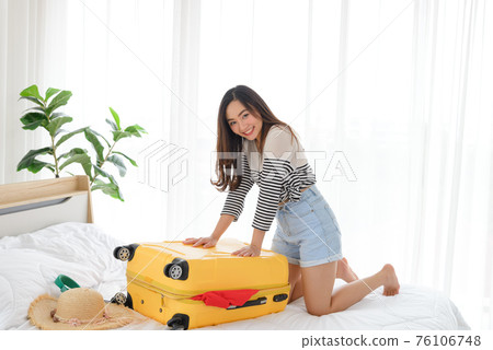 young asian woman in summer casual clothes is smiling and relaxing mood on yellow baggage in her bedroom. It is a time to go to travel in a summer time. Happy tourist woman with yellow suitcase. young asian woman in summer casual clothes is smiling and relaxing mood on yellow baggage in her bedroom. It is a time to go to travel in a summer time. Happy tourist woman with yellow suitcase. 76106748