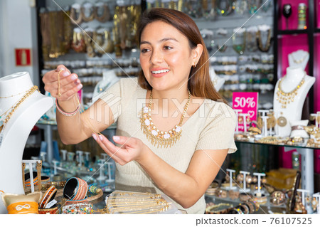 Young adult woman choosing bijouterie in store 76107525