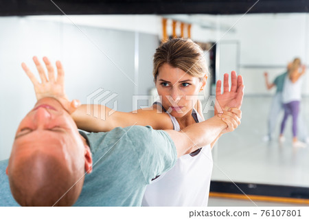 Woman performing palm heel strike while training in gym 76107801