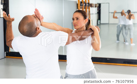 Hispanic girl using palm to launch blow in chin during self defence training 76107956