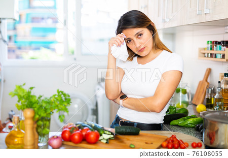 Unhappy mexican housewoman crying during cooking in kitchen Unhappy mexican housewoman crying during cooking in kitchen 76108055
