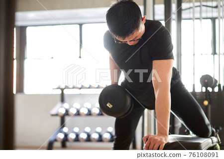 亞洲男子在訓練館裡單手俯身划船 亞洲男子在訓練館裡單手俯身划船 76108091