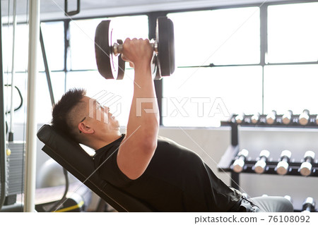 在訓練健身房做傾斜啞鈴飛行的亞洲男子 76108092