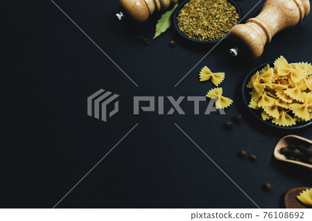 Seasonings, herbs and pasta on black background 76108692