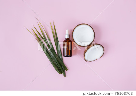 Coconut, green palm leaf on pastel pink background. Bottle of essintial oil Coconut, green palm leaf on pastel pink background. Bottle of essintial oil 76108768