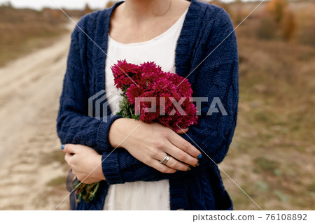 Girl holding red peonies. Present from boyfriend. Blurred background 76108892
