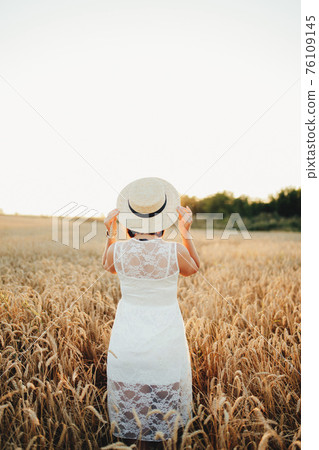 Girl in wheat field, girl's hand and wheat spikelet, sunset on field Girl in wheat field, girl's hand and wheat spikelet, sunset on field 76109145