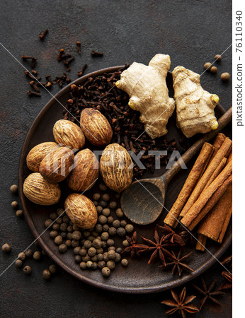 Gingerbread spices on slate - star anise, cinnamon, cloves, nutmeg, ginger, cardamom, black pepper 76110340