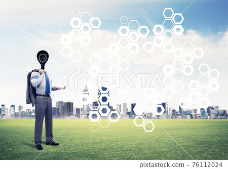 Camera headed man standing on green grass against modern citysca 76112024