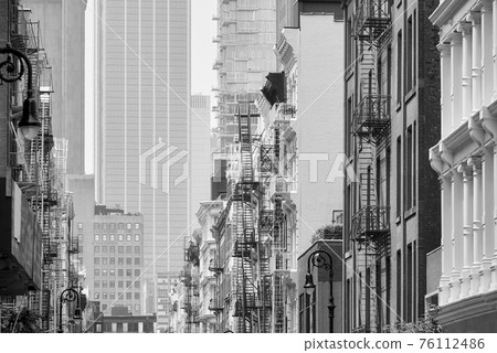 Black and white picture of New York cityscape with old buildings with iron fire escapes, USA. 76112486