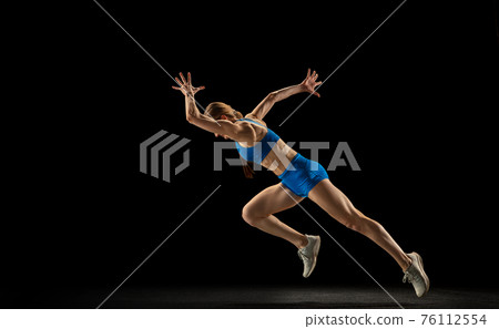 Sportive woman, track athlete training isolated over black studio background. Sportive woman, track athlete training isolated over black studio background. 76112554