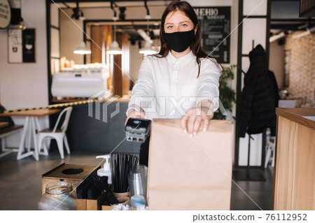 Cashier hand holding credit card reader machine and package with food. Contactless payments concept 76112952