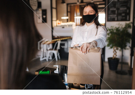 First person view of customer take package with coffee and food from cashier in mask at cafe. Take away food. Quarantine First person view of customer take package with coffee and food from cashier in mask at cafe. Take away food. Quarantine 76112954