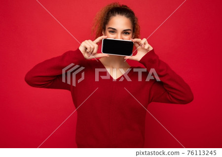 Closeup Photo of happy funny young female person wearing dark red sweater isolated over red 76113245