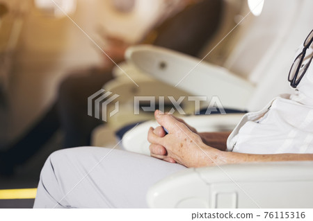 close up Senior Woman's Hand sit on airplane close up Senior Woman's Hand sit on airplane 76115316