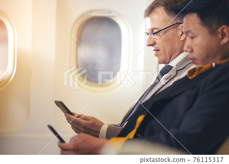 Man travelling by plane and using mobile phone, concept Internet in air stratosphere Man travelling by plane and using mobile phone, concept Internet in air stratosphere 76115317