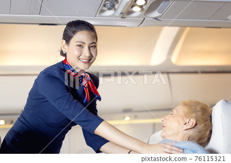 Air hostess or stewardess wearing protective face mask service taking cover cloth for passengers on the airplane , when she sleeping at night 76115321