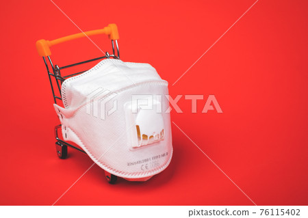 Supermarket cart with protective FFP3 mask on - shopping during Coronavirus COVID-19 epidemy concept 76115402