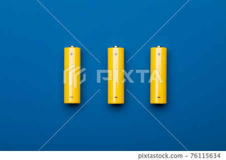 Yellow AA alkaline batteries on blue background Yellow AA alkaline batteries on blue background 76115634