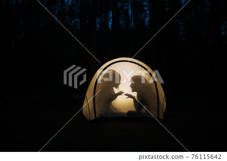 Children making shadow puppets in a camping tent at night Children making shadow puppets in a camping tent at night 76115642