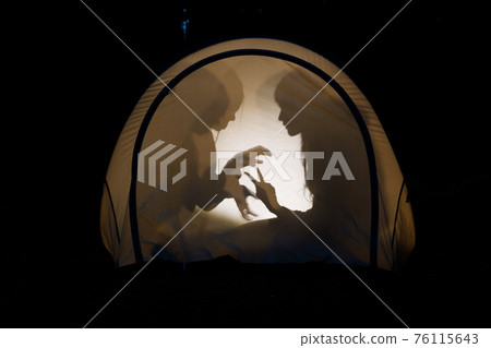 Children making shadow puppets in a camping tent at night Children making shadow puppets in a camping tent at night 76115643