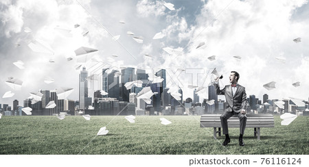 Businessman in summer park announcing something in loudspeaker a 76116124