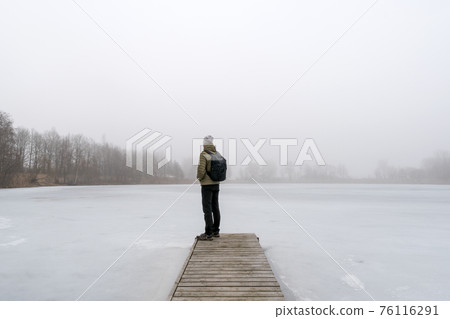 Man standing on a bridge in the fog Man standing on a bridge in the fog 76116291