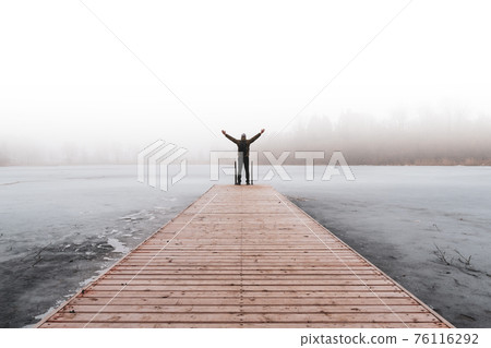 Man on the bridge with raised hands on the foggy morning Man on the bridge with raised hands on the foggy morning 76116292