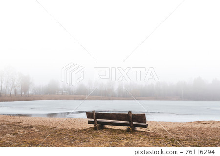 Empty bench at the frozen lake Empty bench at the frozen lake 76116294