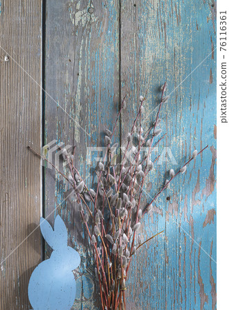 Easter holiday greeting card. Bouquet of willow and wooden bunny on old blue paint wooden background; vertical picture Easter holiday greeting card. Bouquet of willow and wooden bunny on old blue paint wooden background; vertical picture 76116361