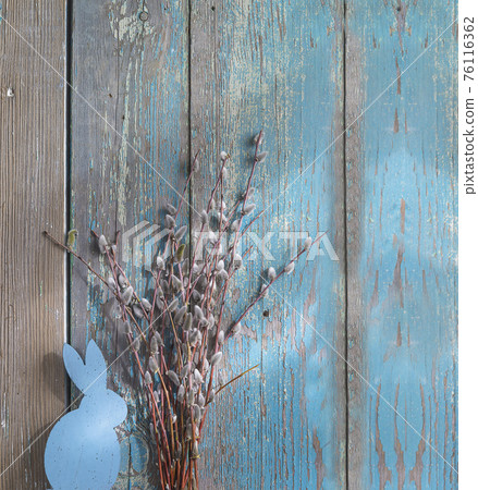 Easter holiday greeting card. Bouquet of willow and wooden bunny on old blue paint wooden background; vertical picture Easter holiday greeting card. Bouquet of willow and wooden bunny on old blue paint wooden background; vertical picture 76116362