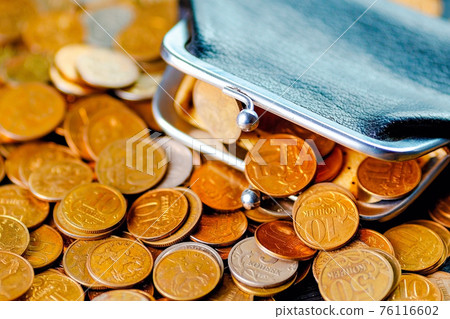 An old black wallet sits on top of a pile of Russian coins. The concept of inflation and poverty. An old black wallet sits on top of a pile of Russian coins. The concept of inflation and poverty. 76116602