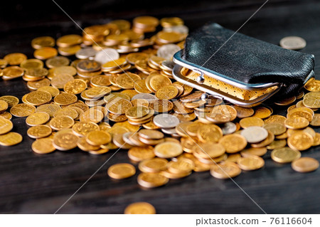 An old black wallet sits on top of a pile of Russian coins. The concept of inflation and poverty. An old black wallet sits on top of a pile of Russian coins. The concept of inflation and poverty. 76116604