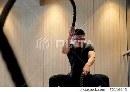 Asian man training on a battle rope Asian man training on a battle rope 76116645