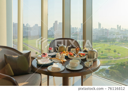 English afternoon tea, set beverages snacks desserts on table at restaurant, Bangkok City. The Royal Bangkok Sports Club Park with city view landscape. Food and drink. 76116812