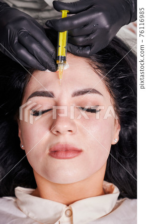 Brunette girl in cosmetology office during plasmolifting procedure lying with closed eyes Brunette girl in cosmetology office during plasmolifting procedure lying with closed eyes 76116985