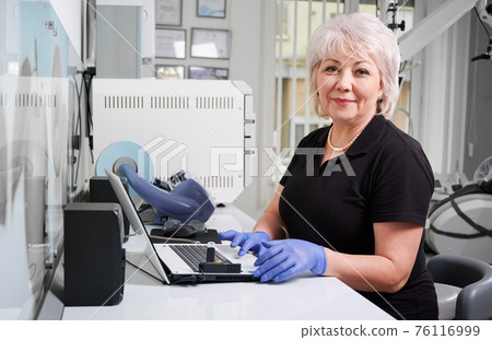 Portrait of female doctor sitting at computer in dental clinic Portrait of female doctor sitting at computer in dental clinic 76116999