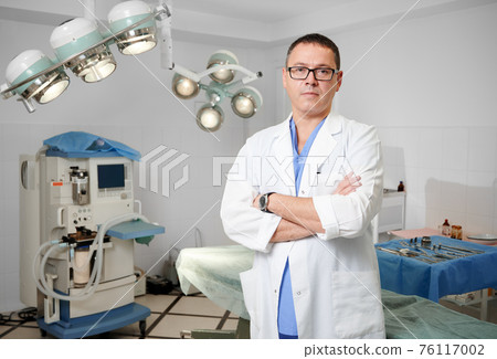 Male doctor in lab coat standing in operating room. Male doctor in lab coat standing in operating room. 76117002