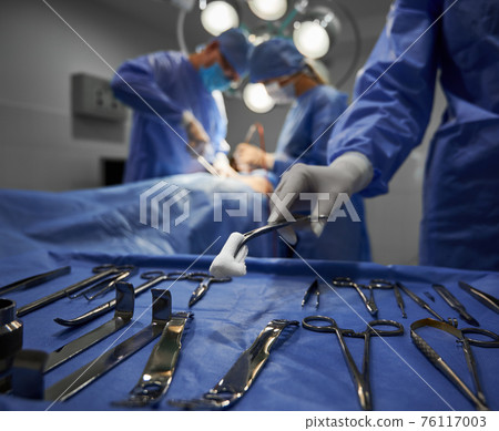 Doctors using medical instruments during plastic surgery. 76117003