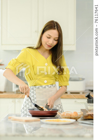 Woman cooking rice with vegetables in kitchen Woman cooking rice with vegetables in kitchen 76117641
